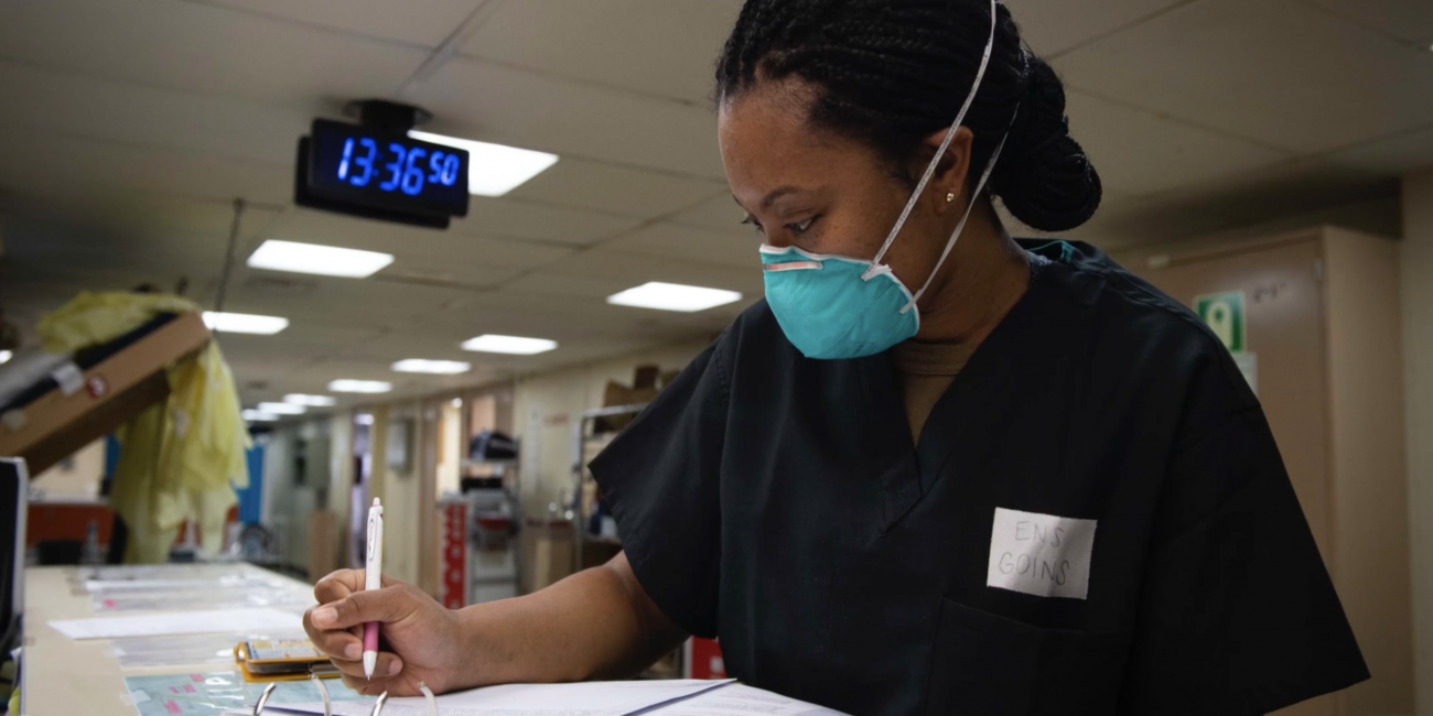 Image of female nurse in scrubs taking down notes